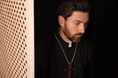 Catholic priest wearing cassock in confessional booth
