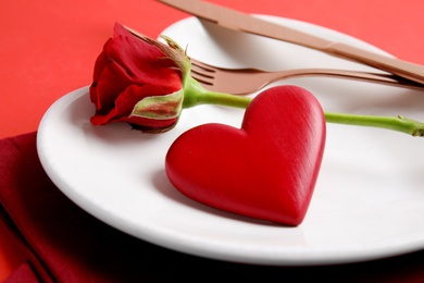 Photo of Elegant table setting for romantic dinner on red background, closeup. Valentine's day celebration