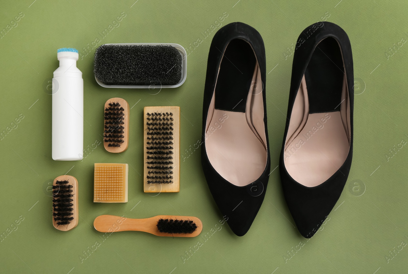 Photo of Stylish footwear with shoe care accessories on green background, flat lay