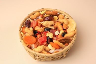 Wicker basket with mixed dried fruits and nuts on beige background