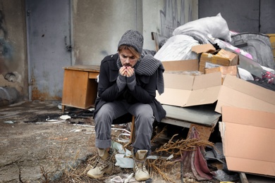 Photo of Poor young man sitting near garbage at dump
