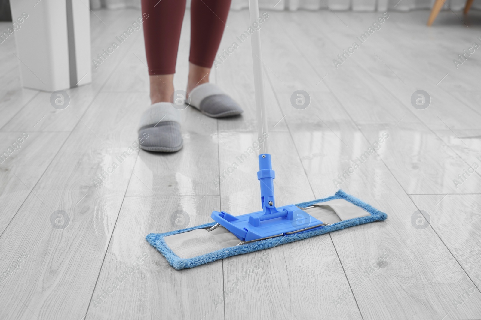 Photo of Woman cleaning floor with mop indoors, selective focus