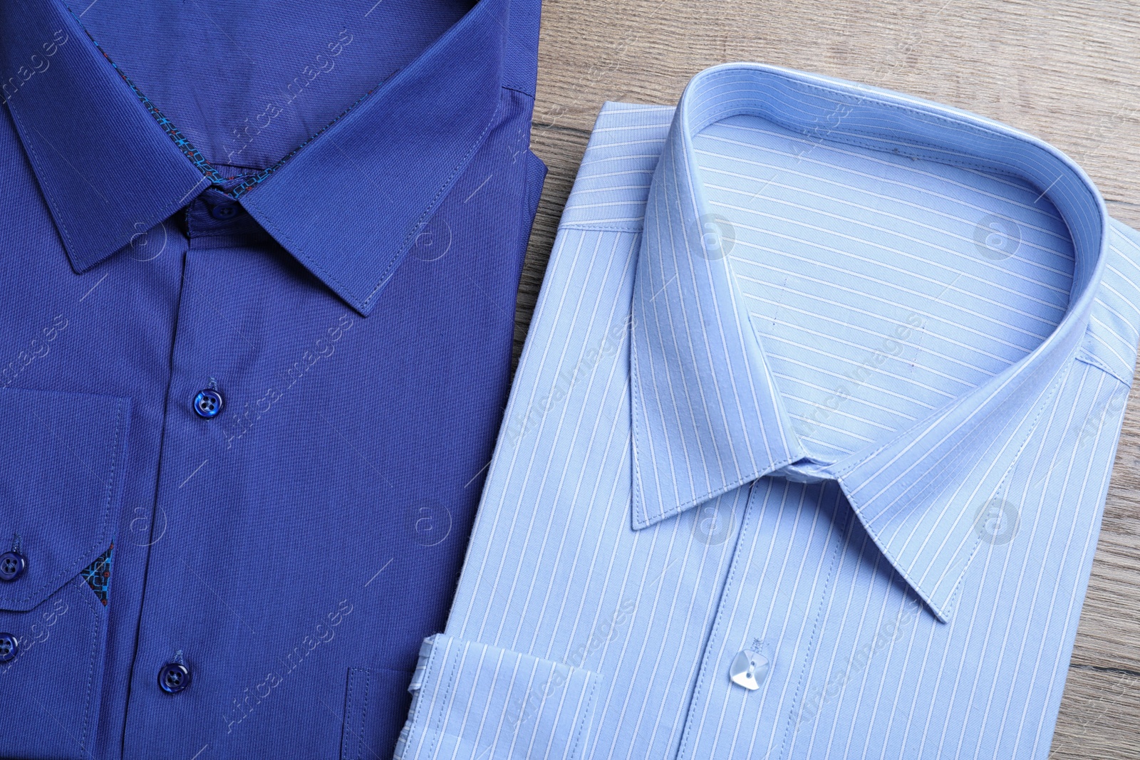 Photo of Stylish folded shirts on wooden table, flat lay. Dry-cleaning service