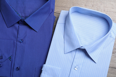 Stylish folded shirts on wooden table, flat lay. Dry-cleaning service