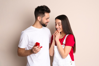 Photo of Man with engagement ring making marriage proposal to girlfriend on beige background