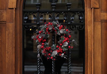 Photo of Beautiful Christmas wreath hanging on glass door