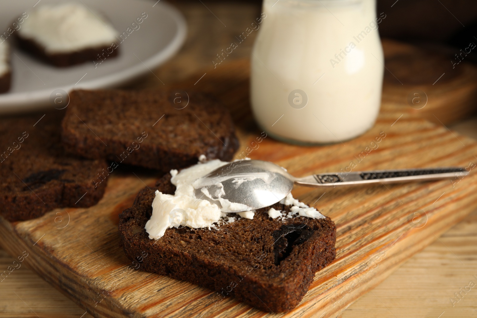 Photo of Delicious cream cheese and bread on wooden table