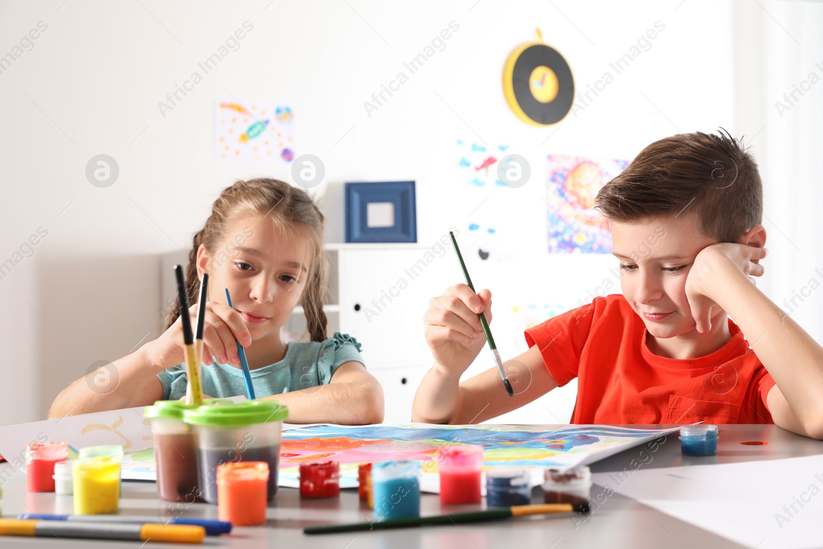 Photo of Little children painting picture at table indoors