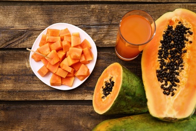 Flat lay composition with fresh papayas and juice on wooden table