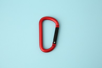 Photo of One red carabiner on light blue background, top view