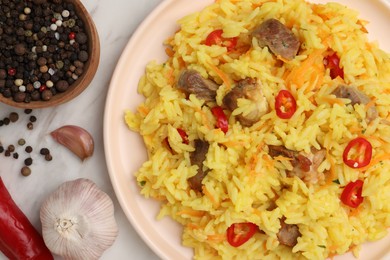 Delicious pilaf with meat and ingredients on white marble table, top view