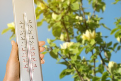 Image of Woman holding thermometer outdoors in spring, closeup