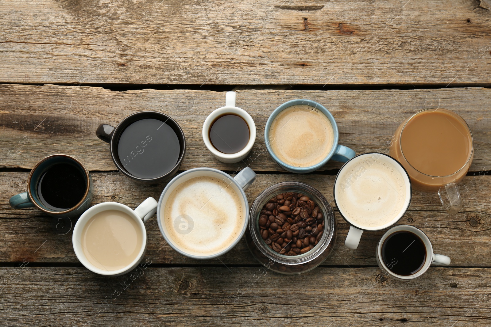 Photo of Different coffee drinks in cups and beans on wooden table, flat lay