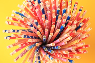 Many paper drinking straws on orange background, closeup