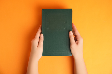 Photo of Woman with book on orange background, top view. Space for design