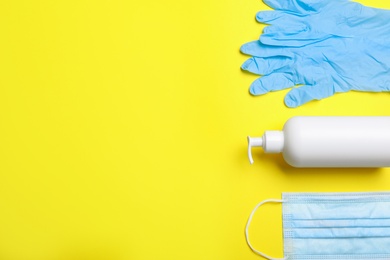 Photo of Medical gloves, mask and hand sanitizer on yellow background, flat lay. Space for text