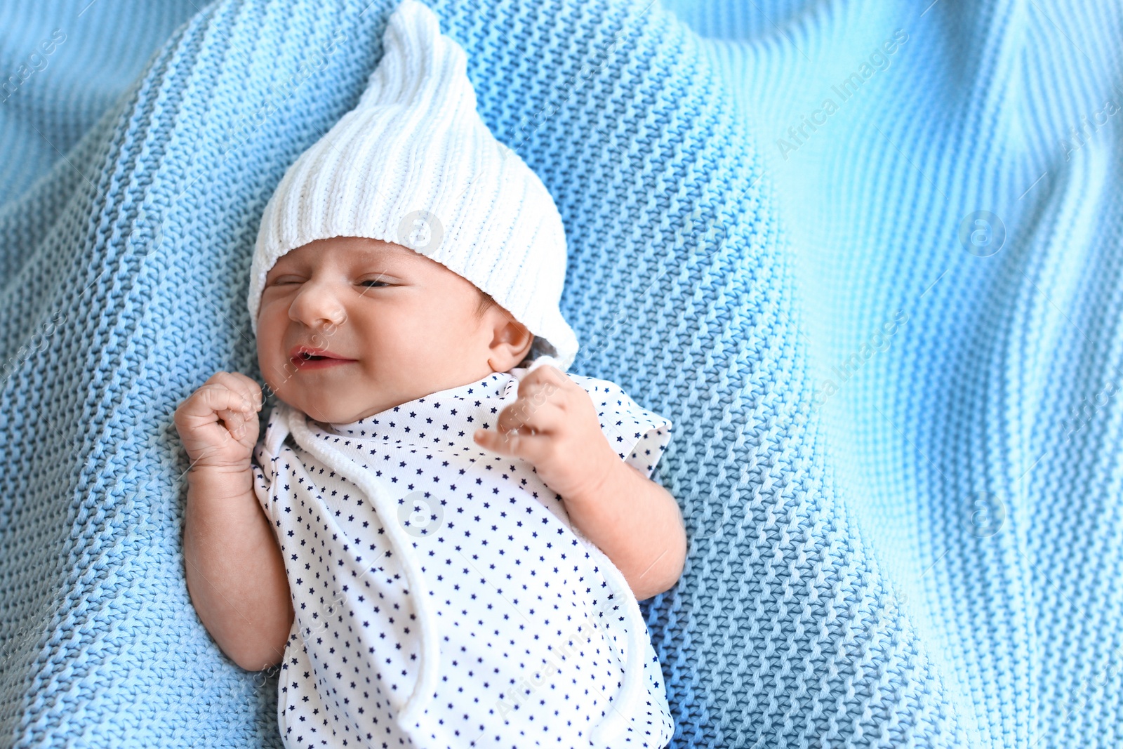 Photo of Cute little baby in hat lying on light blue plaid, top view. Space for text