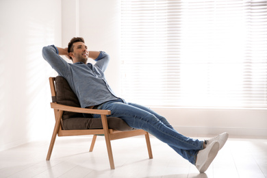 Photo of Young man relaxing in armchair near window at home