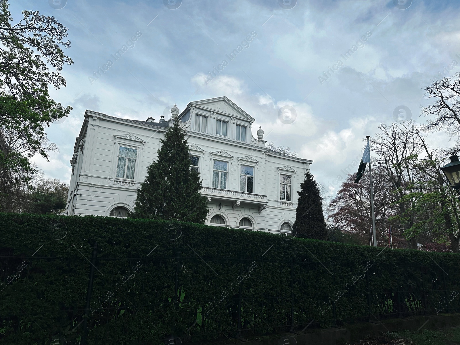 Photo of Beautiful white building behind green hedge outdoors