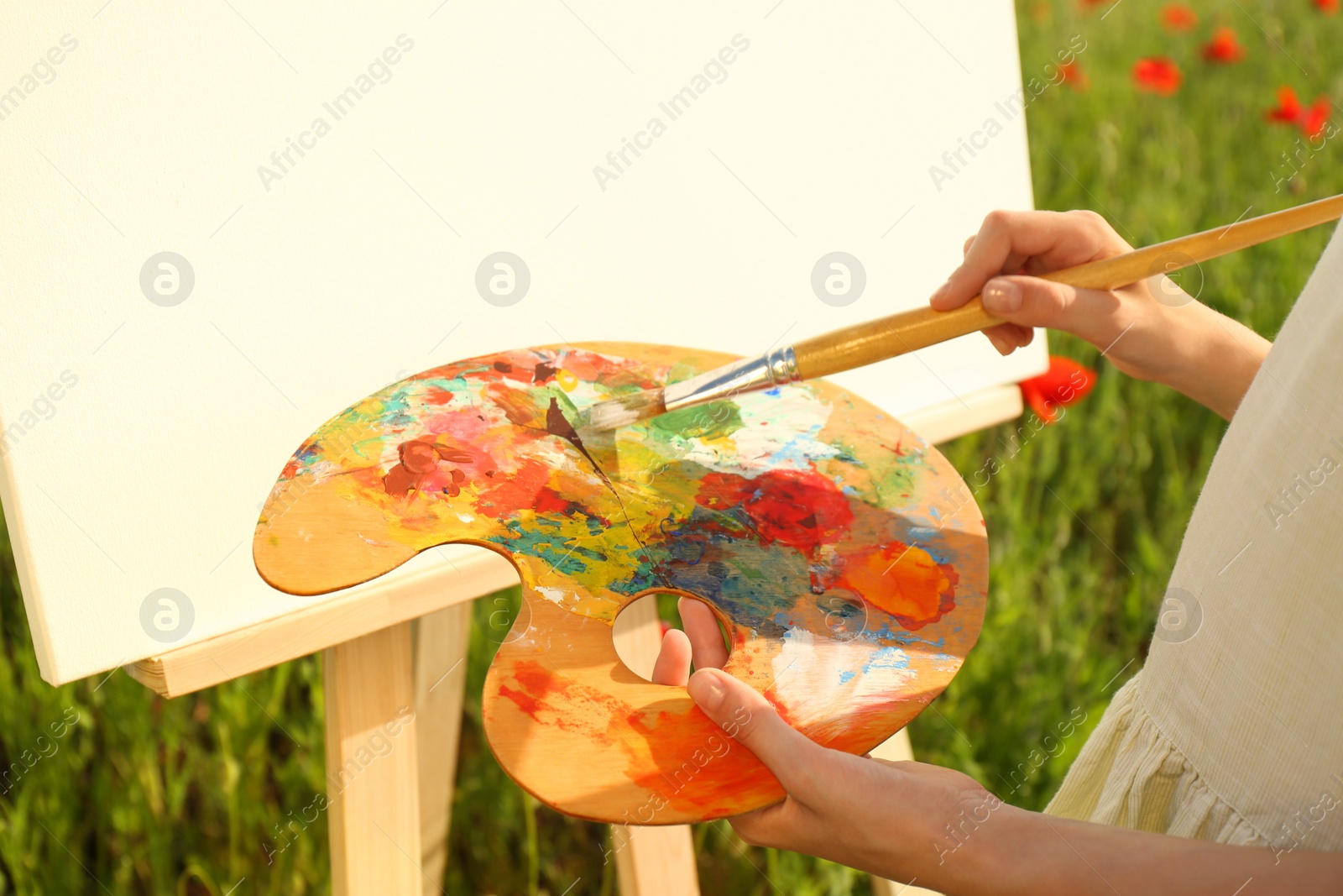 Photo of Little girl painting on easel in countryside, closeup