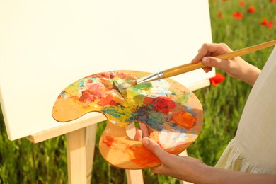 Photo of Little girl painting on easel in countryside, closeup