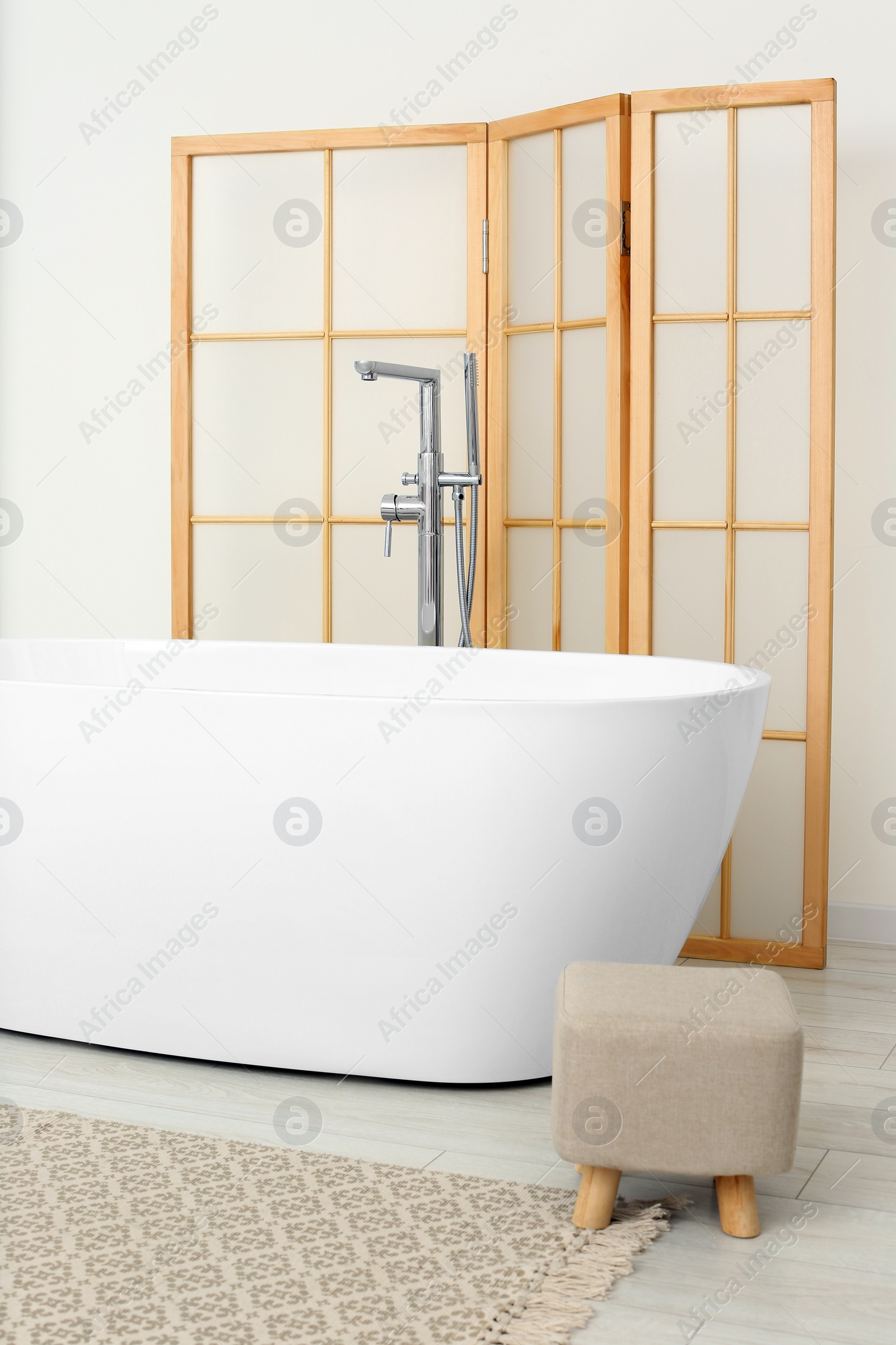 Photo of Beautiful white tub and ottoman in bathroom. Interior design