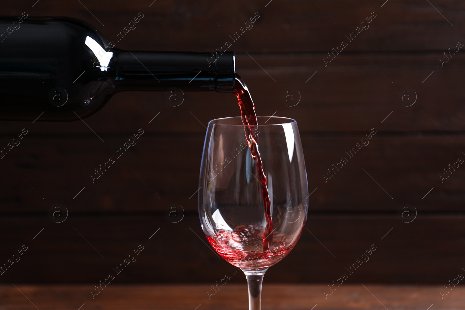 Photo of Pouring delicious red wine into glass on blurred background