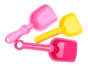 Photo of Bright plastic toy shovels on white background, top view