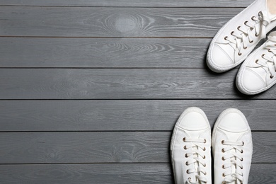 Photo of White sneakers and space for text on wooden background, top view. Stylish shoes
