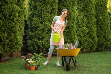 Happy young woman watering plants in garden