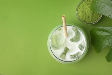 Glass of tasty iced matcha latte, leaf and powder on light green background, flat lay. Space for text