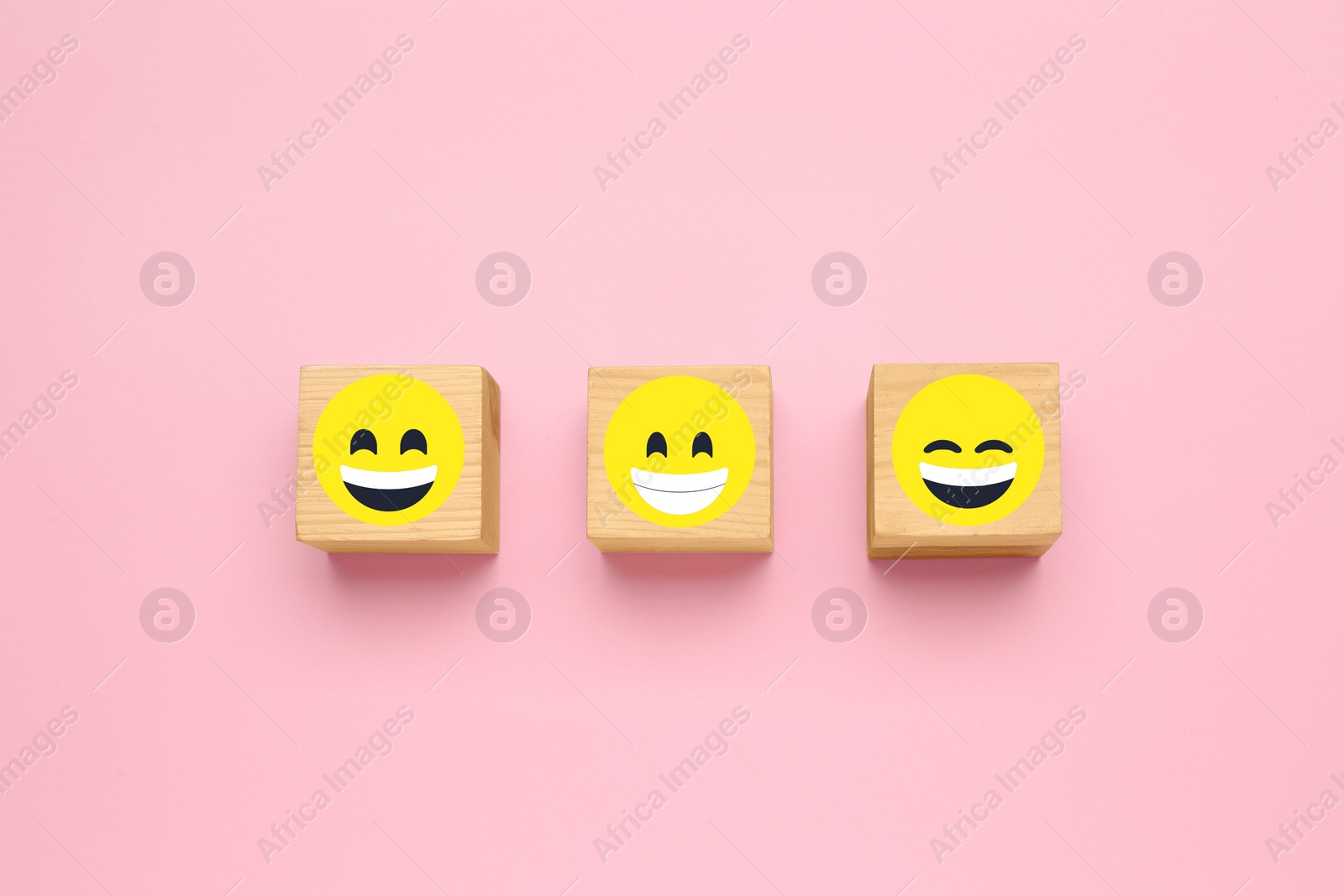 Image of Wooden cubes with different emoticons on pink background, flat lay