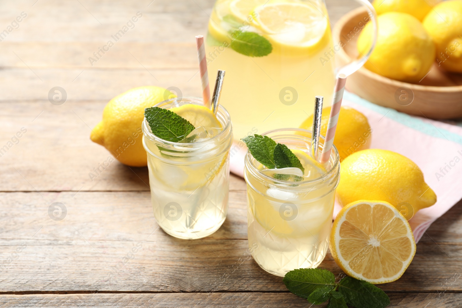 Photo of Natural lemonade with mint and fresh fruits on wooden table. Summer refreshing drink