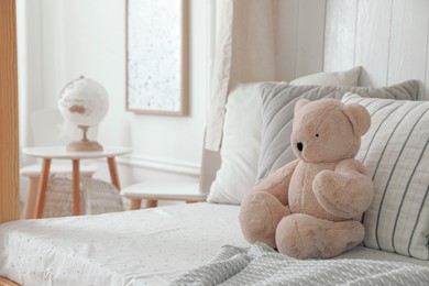 Comfortable bed with cushions and toy in room. Interior design
