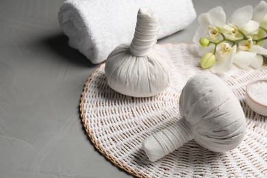 Photo of Herbal massage bags and rolled towel on grey table. Spa supply