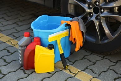 Photo of Car cleaning products and bucket near automobile outdoors on sunny day