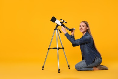 Photo of Happy astronomer with telescope on orange background, space for text
