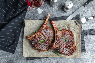 Photo of Delicious beef steaks served on grey table, flat lay