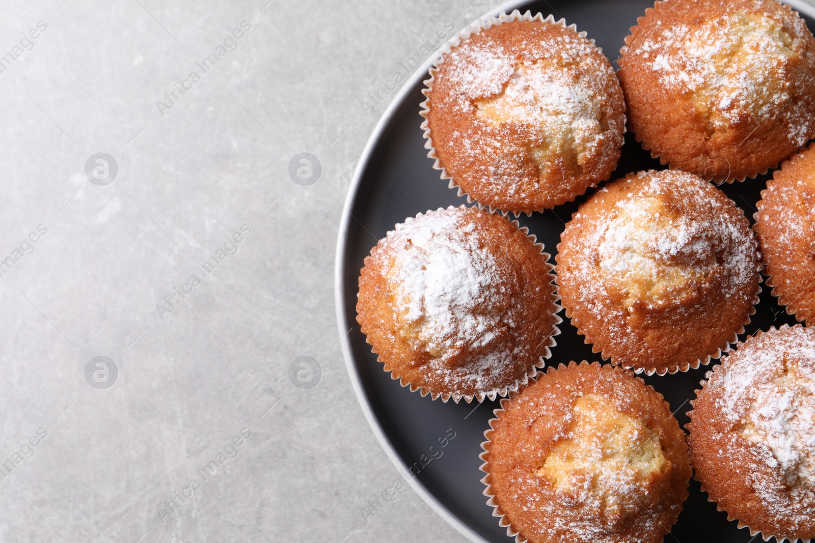 Photo of Delicious sweet muffins on light grey textured table, top view. Space for text