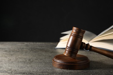 Photo of Law concept. Gavel and book on grey textured table against black background, space for text