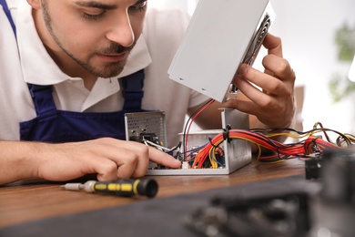 Male technician repairing power supply unit at table, closeup