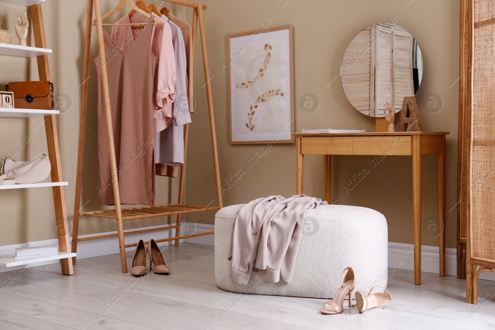 Photo of Stylish ottoman, console table and clothing rack in dressing room. Interior design