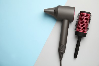Hair dryer and round brush on color background, flat lay. Space for text