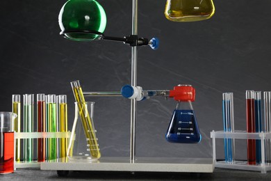 Retort stand and laboratory glassware with liquids on table against grey background