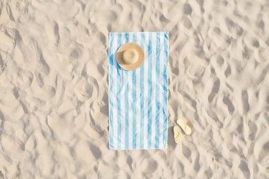Image of Striped beach towel, straw hat and flip flops on sand, aerial view