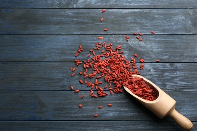 Scoop and dried goji berries on blue wooden table, top view with space for text. Healthy superfood