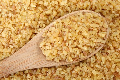 Spoon on pile of uncooked bulgur, top view