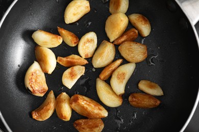 Frying pan with fried garlic cloves and rosemary, top view