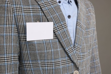 Man with blank badge on grey background, closeup