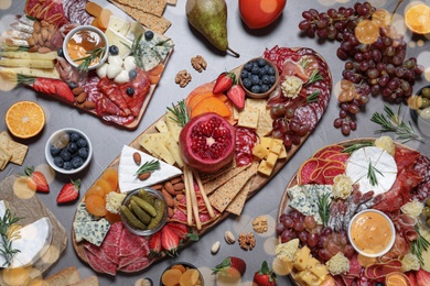 Photo of Wooden plates with different delicious snacks on grey table, flat lay